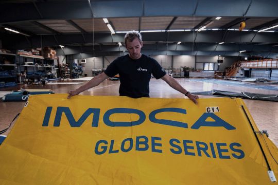 Le skipper Thomas Ruyant présente le logo IMOCA sur une grand voile